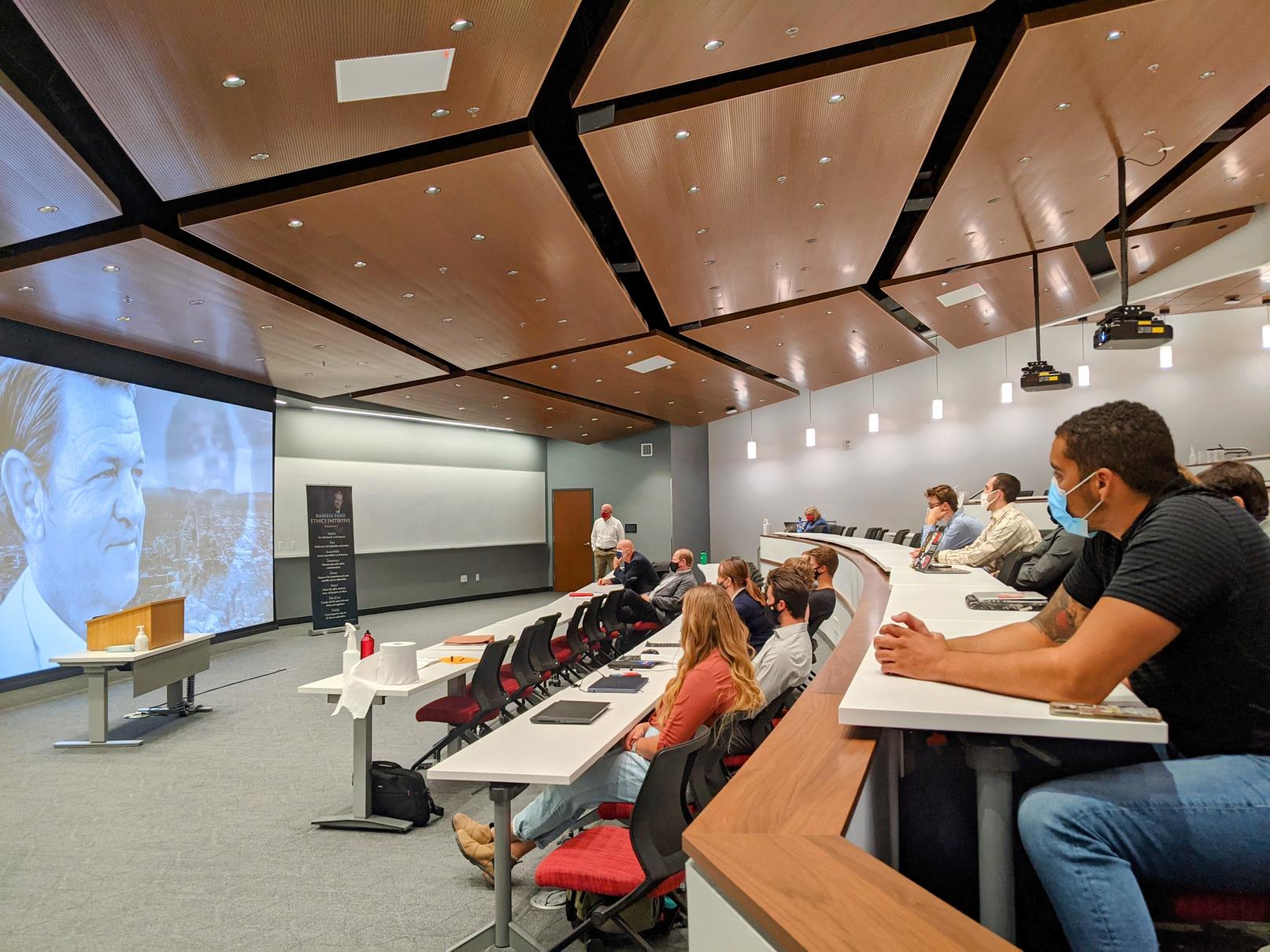 Students listening to presentation in brightly lit auditorium