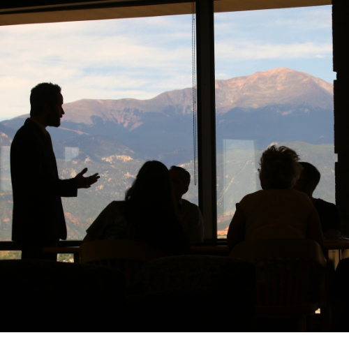 Professionals in discussion with Pikes Peak in background. 