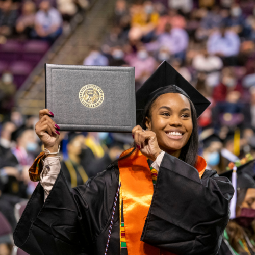 Image of UCCS grad holding up diploma.