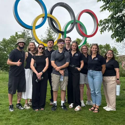 Photo of students standing in front of the Olympic rings in London