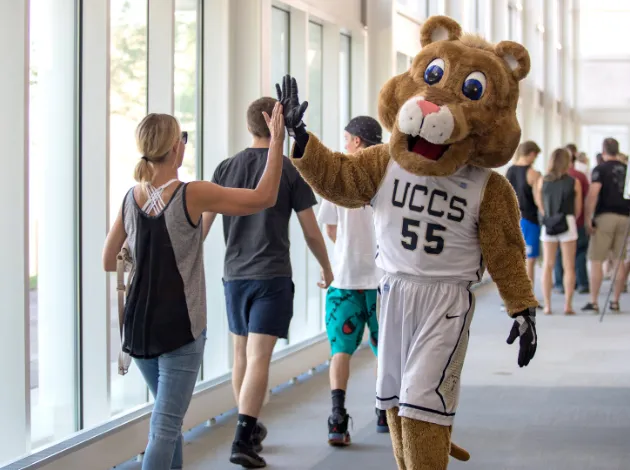 Student high-fiving Clyde in Dwire Hall.