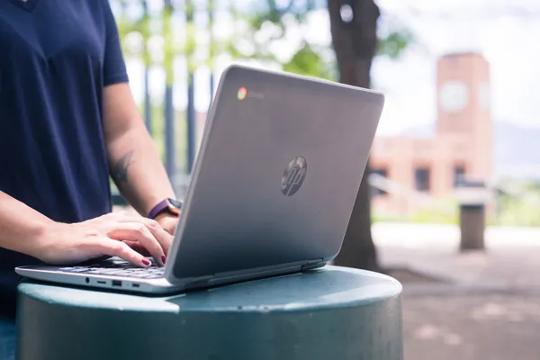 Someone using a laptop in front of the UCCS bell tower