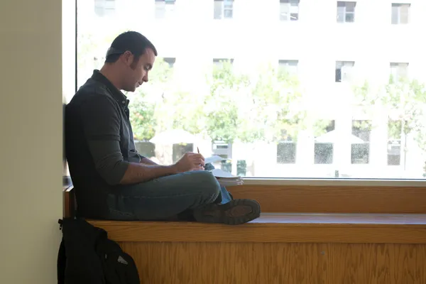 Male student studying in front of a window