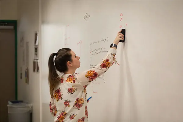 Student erasing an equation on a white board