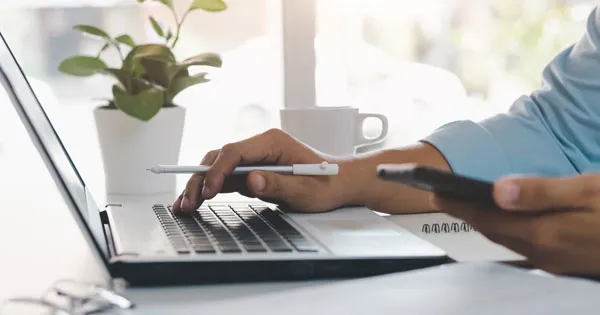 Person looking at their phone and typing on the computer