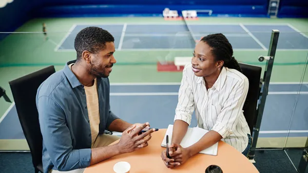 People talking in front of a tennis court